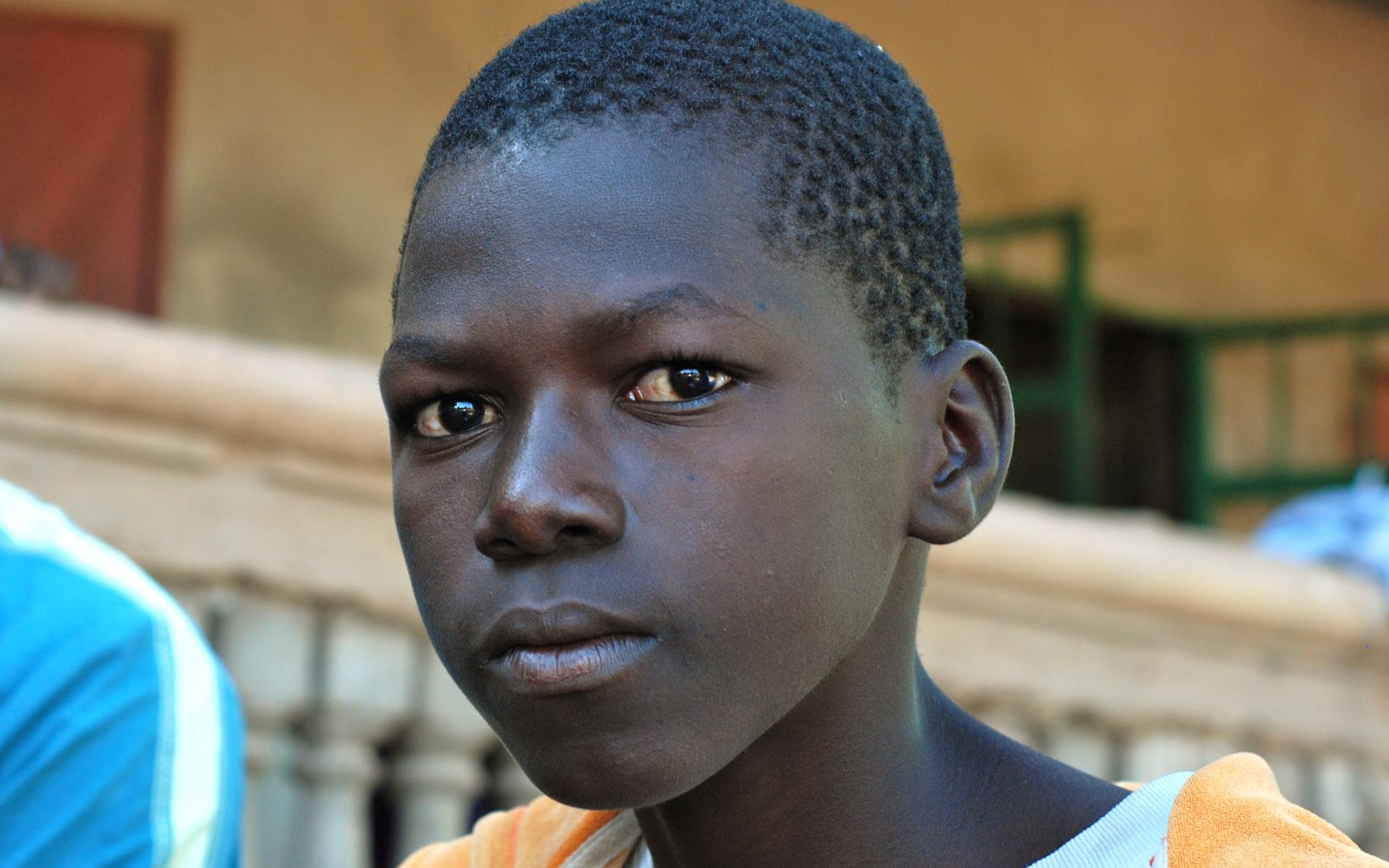 Bubacarr, 15, sits outside his home in Gambia's remote Upper River region. 
