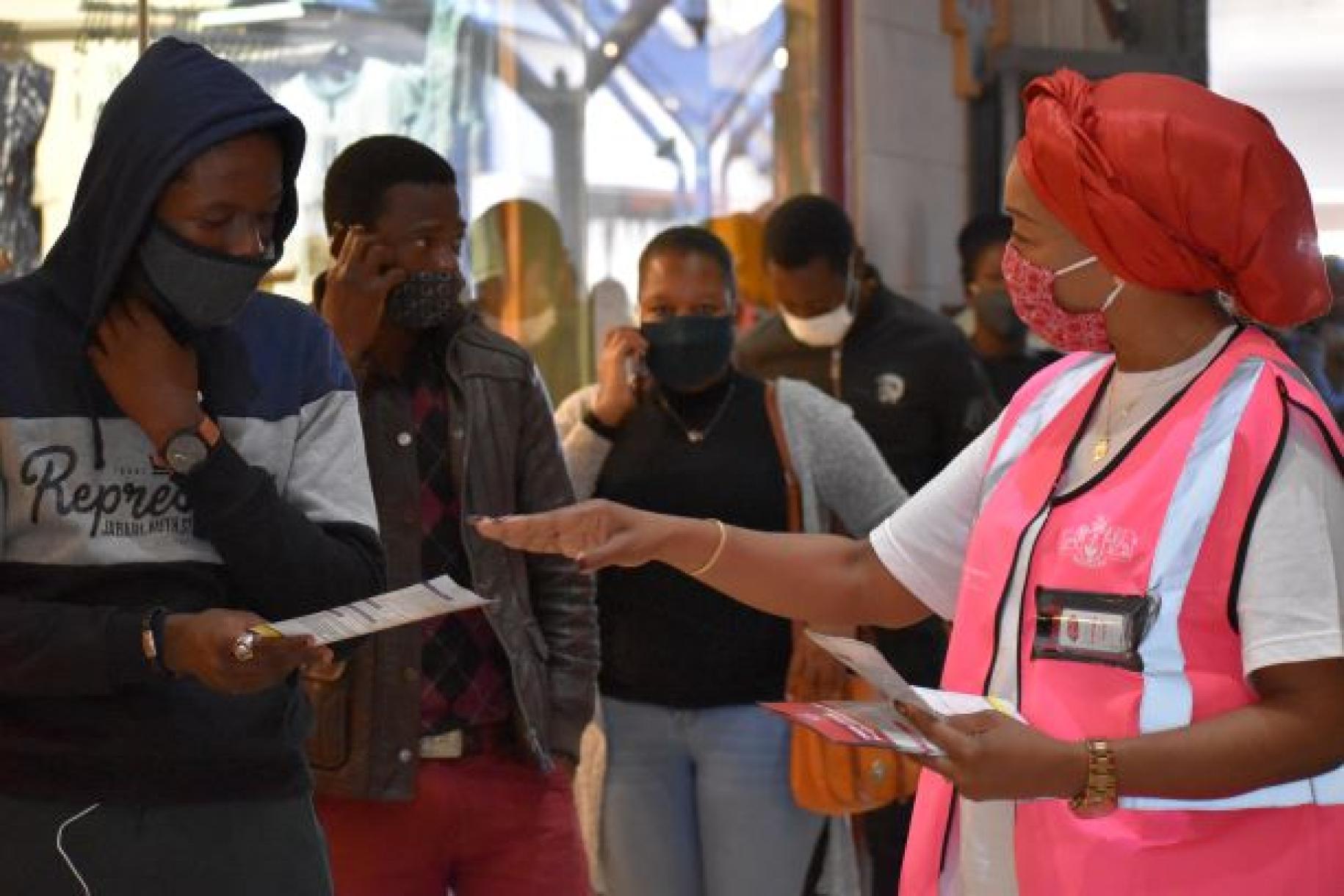 تساعد المنسقة المقيمة ناتالي ندونغو سيه في توزيع كتيبات تحتوي على معلومات حول الوقاية من كوفيد-19 على الجمهور في مدينة مباباني.