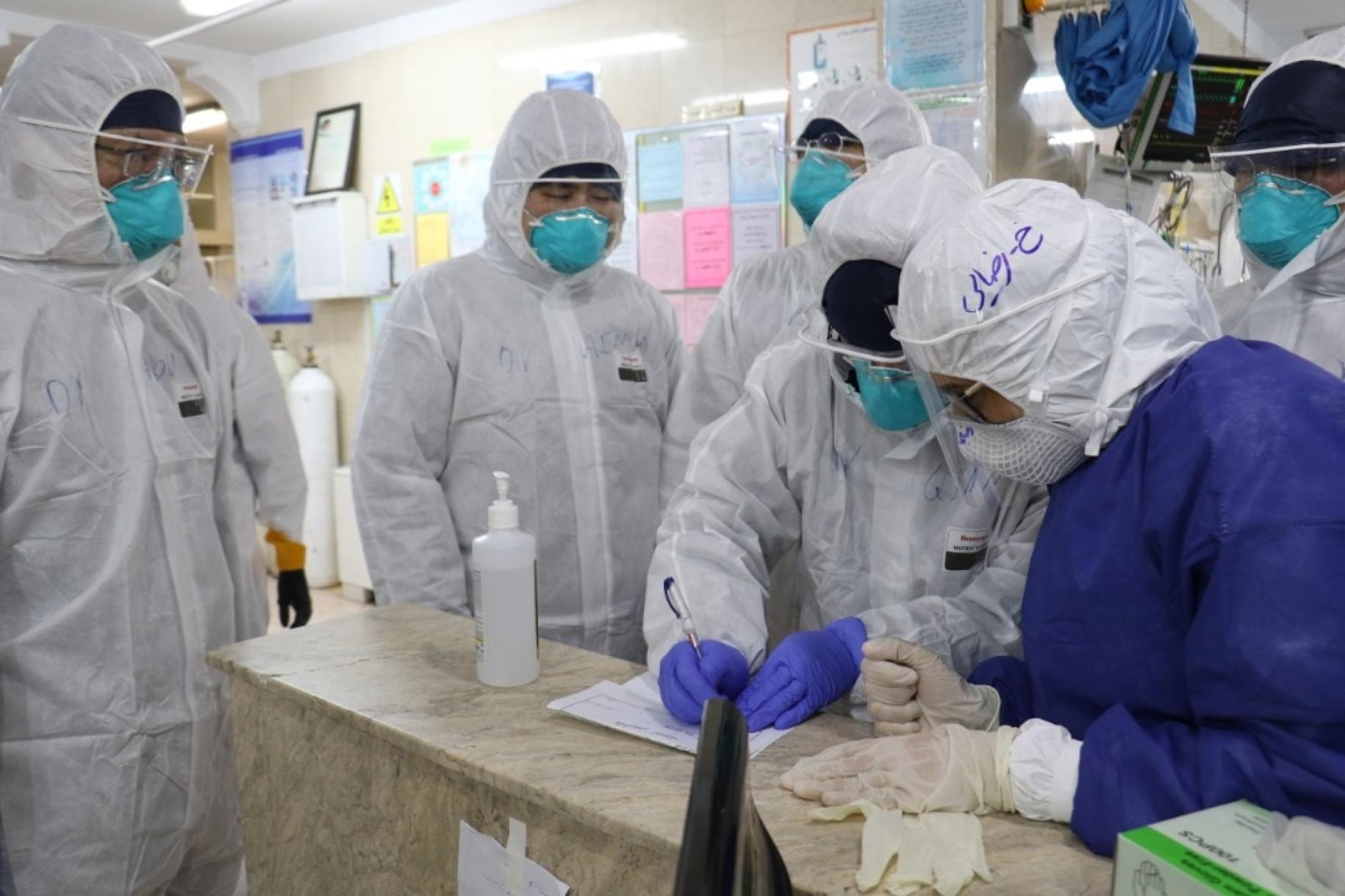 WHO staff visited the Masih Daneshvari Hospital in North of Tehran. All wearing head-to-toe personal protective equipment, they review lab documentation. 