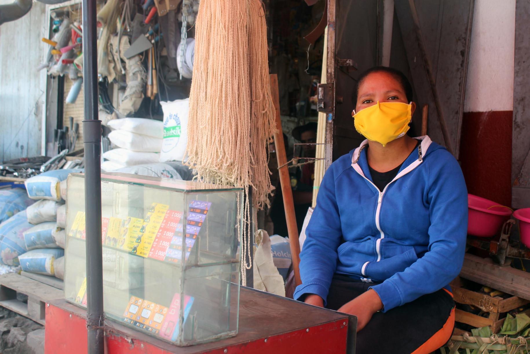 A woman is shown wearing a protective mask at the small shop she runs at the market in Antananarivo, Madagascar.