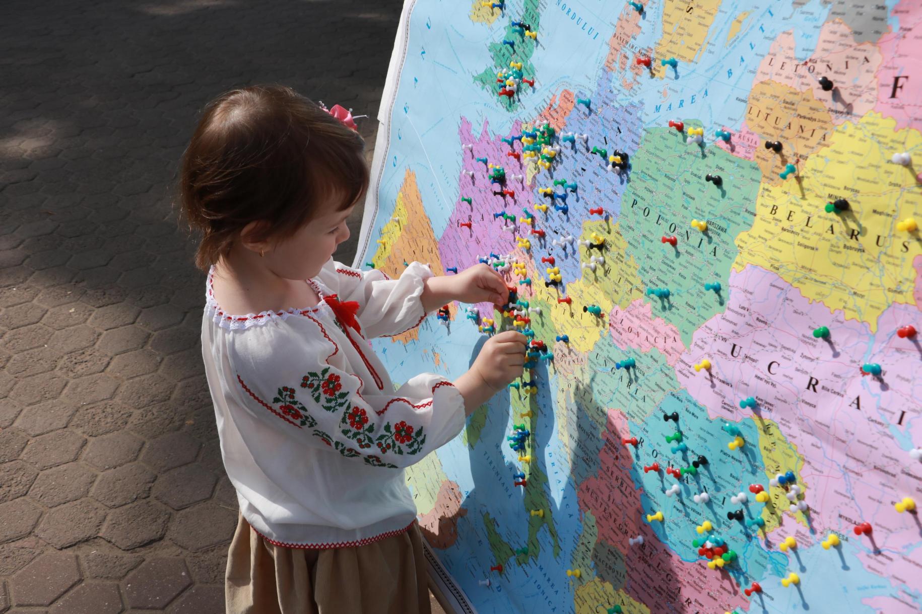 A little girl touches the thumbtacks placed on a map of the country.