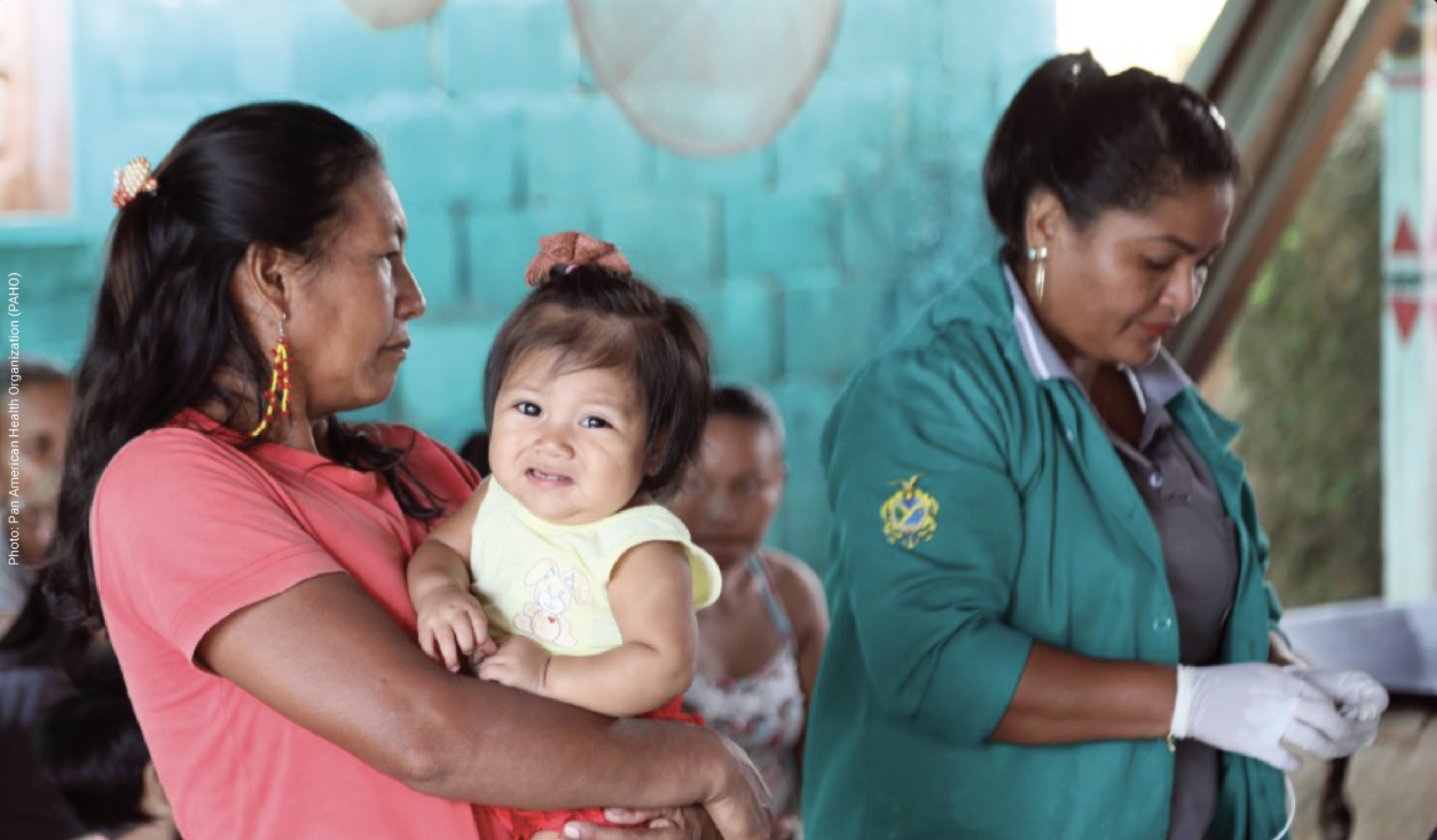 Una mujer indígena sostiene a una niña mientras espera ser atendida por una trabajadora de la salud.