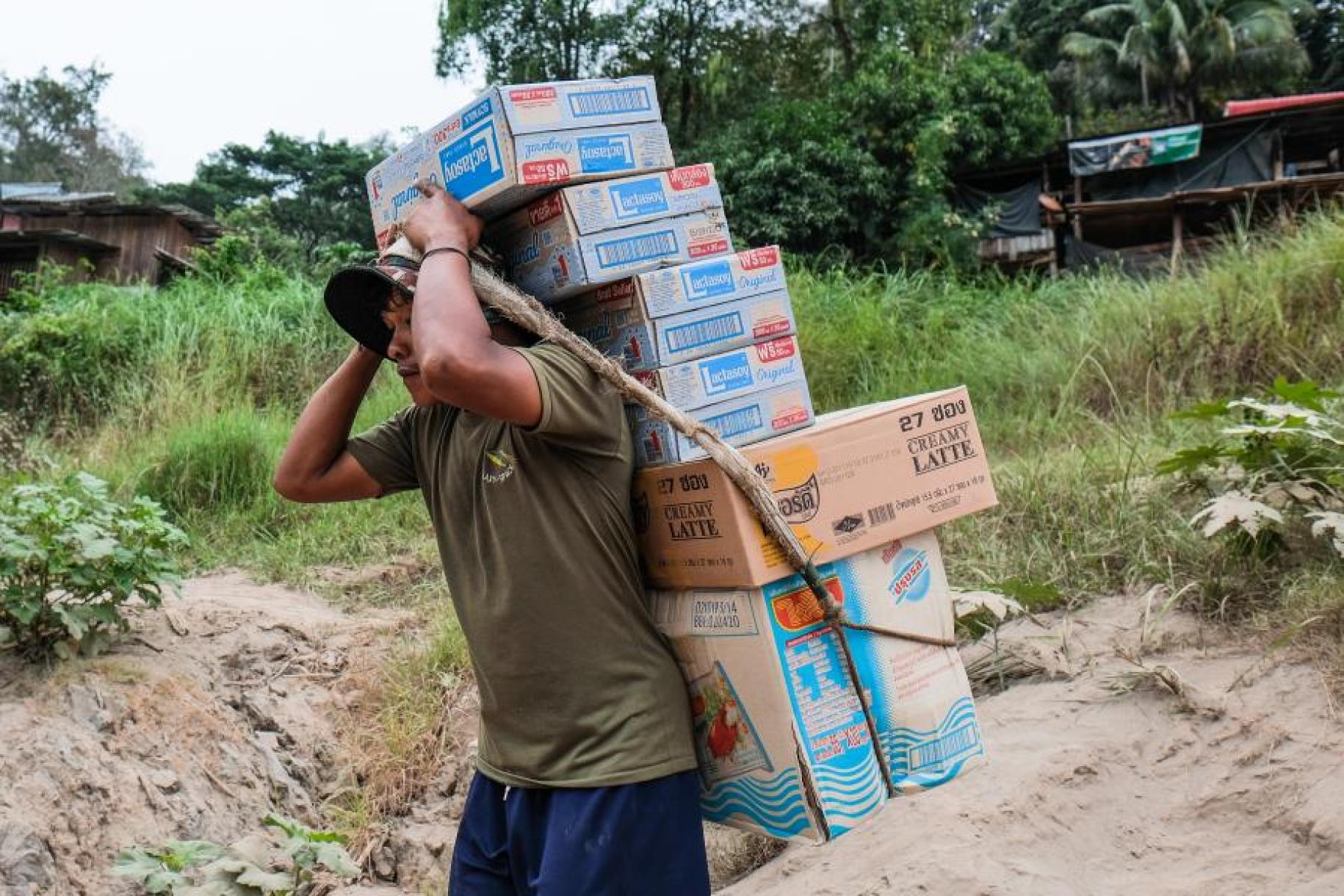 A migrant worker in Thailand carries boxes on his back using a rope to hold them all together.