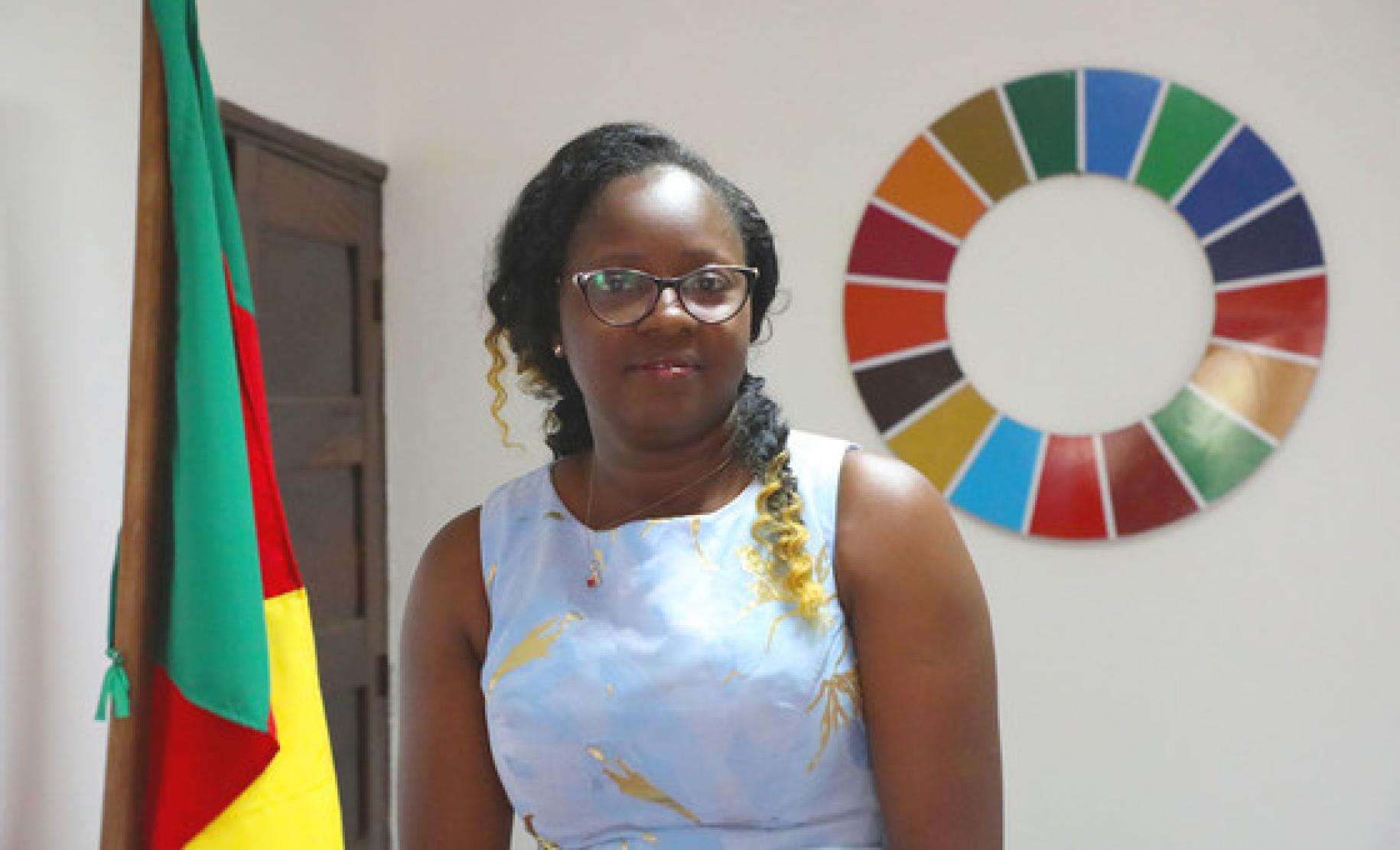 Photo showsCecile Mawe, founder and President of Jeunes en Action pour le Développement Durable (JADD), Cameroon., besides the Cameroon flag and the SDG wheel.