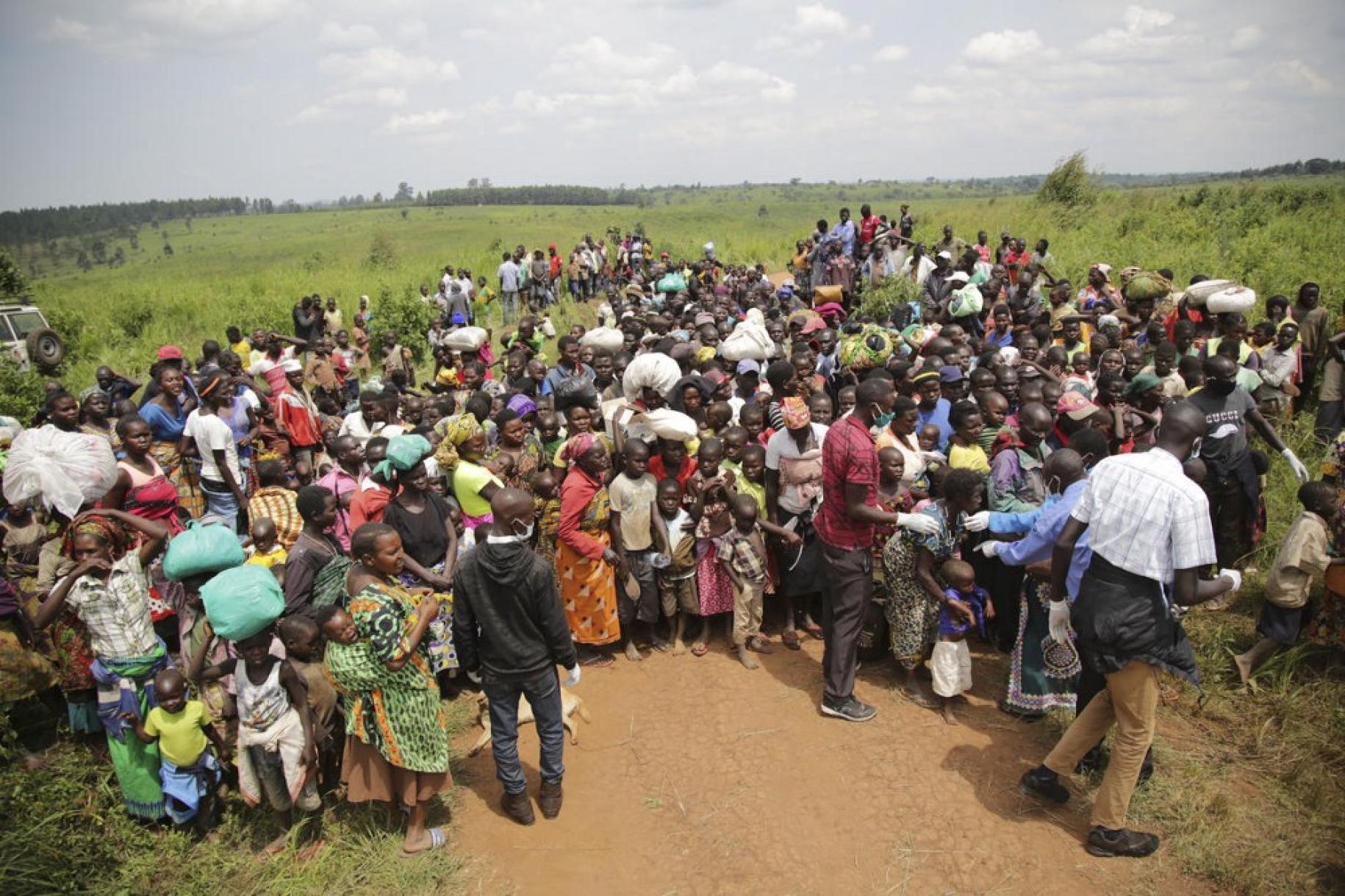 Plusieurs dizaines de demandeurs d'asile congolais attendent dans un champ de pouvoir passer un examen médical près de la frontière ougandaise, le 1er juillet 2020.