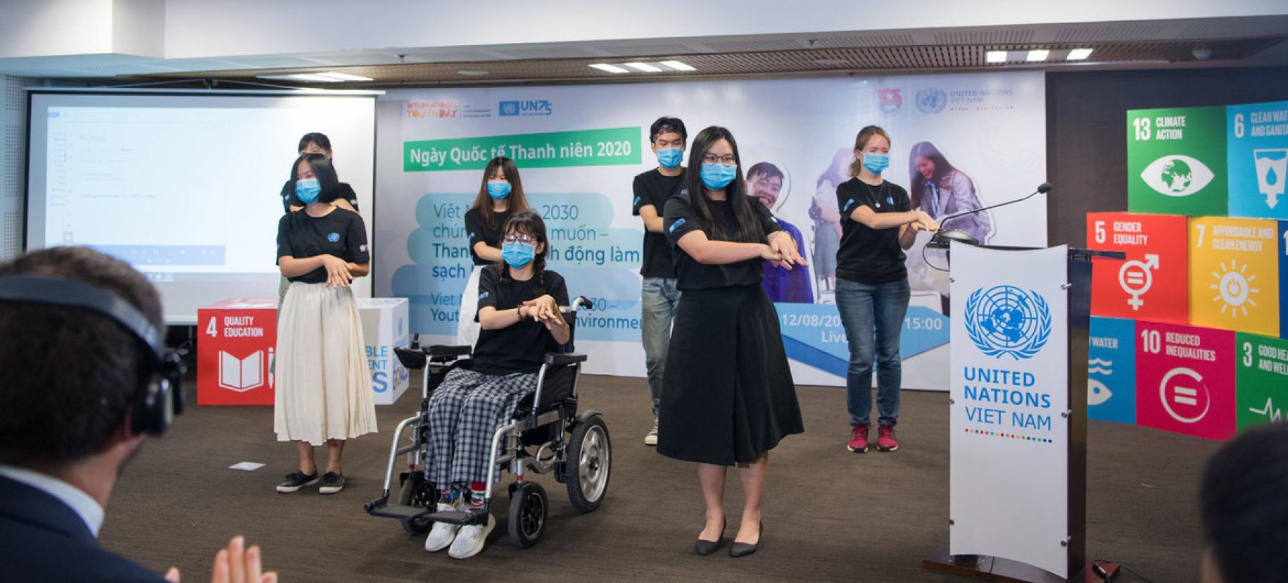 De jeunes filles et de jeunes garçons exécutent une chorégraphie lors des festivités organisées pour la Journée internationale de la jeunesse 2020. L'une des participantes, au centre de l'image, est en fauteuil roulant. Tous portent un masque de protection respiratoire.