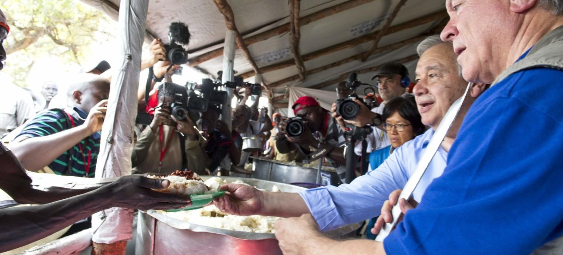 يقدّم الأمين العام أنطونيو غوتيريش مع المدير التنفيذي لبرنامج الأغذية العالمي ديفيد بيسلي وجبات غذائية في منطقة الاستقبال للاجئين الوافدين حديثًا في مستوطنة إمفيبي في أوغندا.