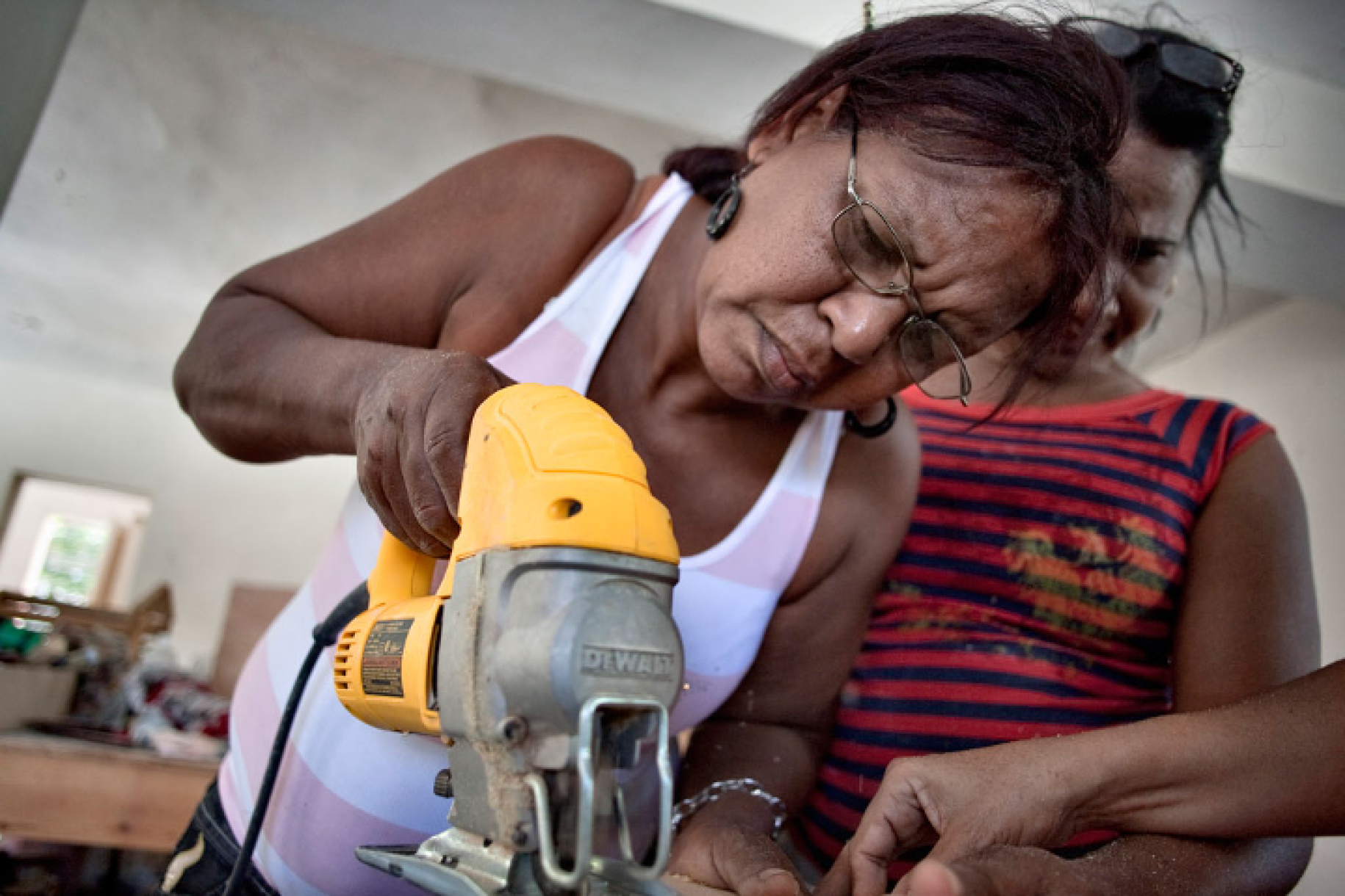 A woman uses a handsaw on the job at a workshop in the Dominican Republic. 