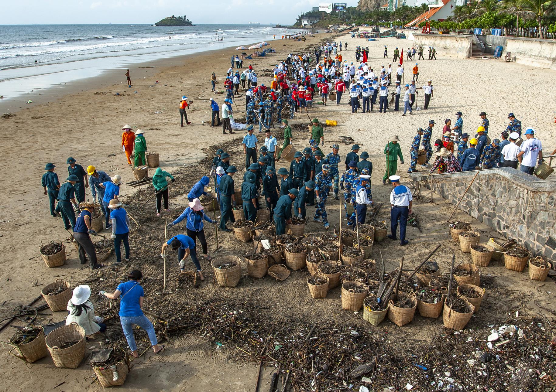 Las personas trabajan juntas para recoger la basura que llega flotando desde el mar.