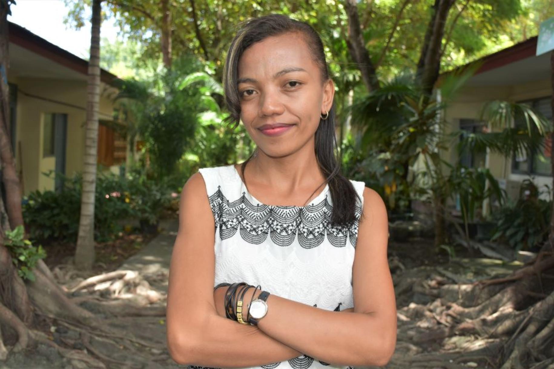 Norberta V. Soares da Cruz stands in outside in front of two homes with her arms crossed as she looks at the camera.