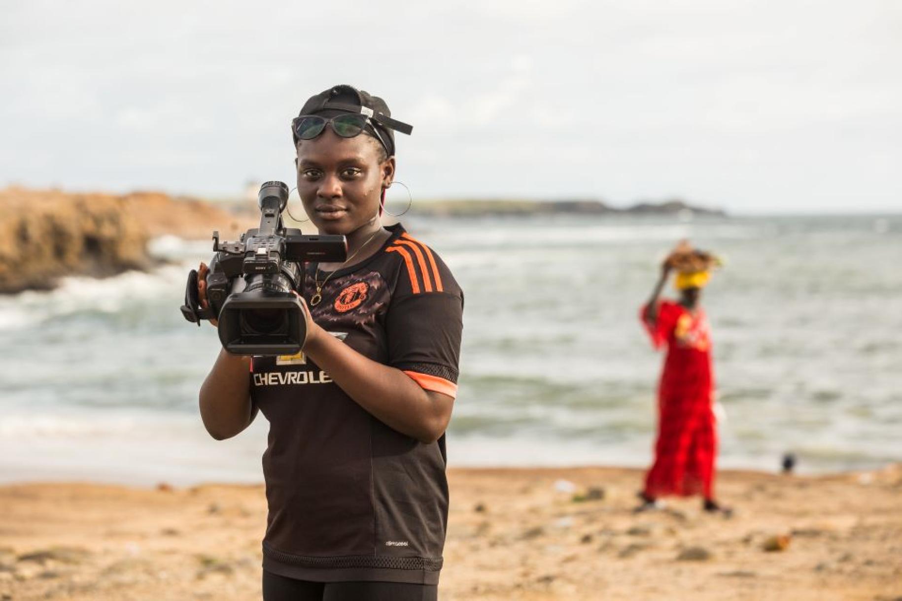 Oumou Kalsoum Diop, de 18 años, posa para un retrato con su cámara de vídeo en la playa de Dakar.