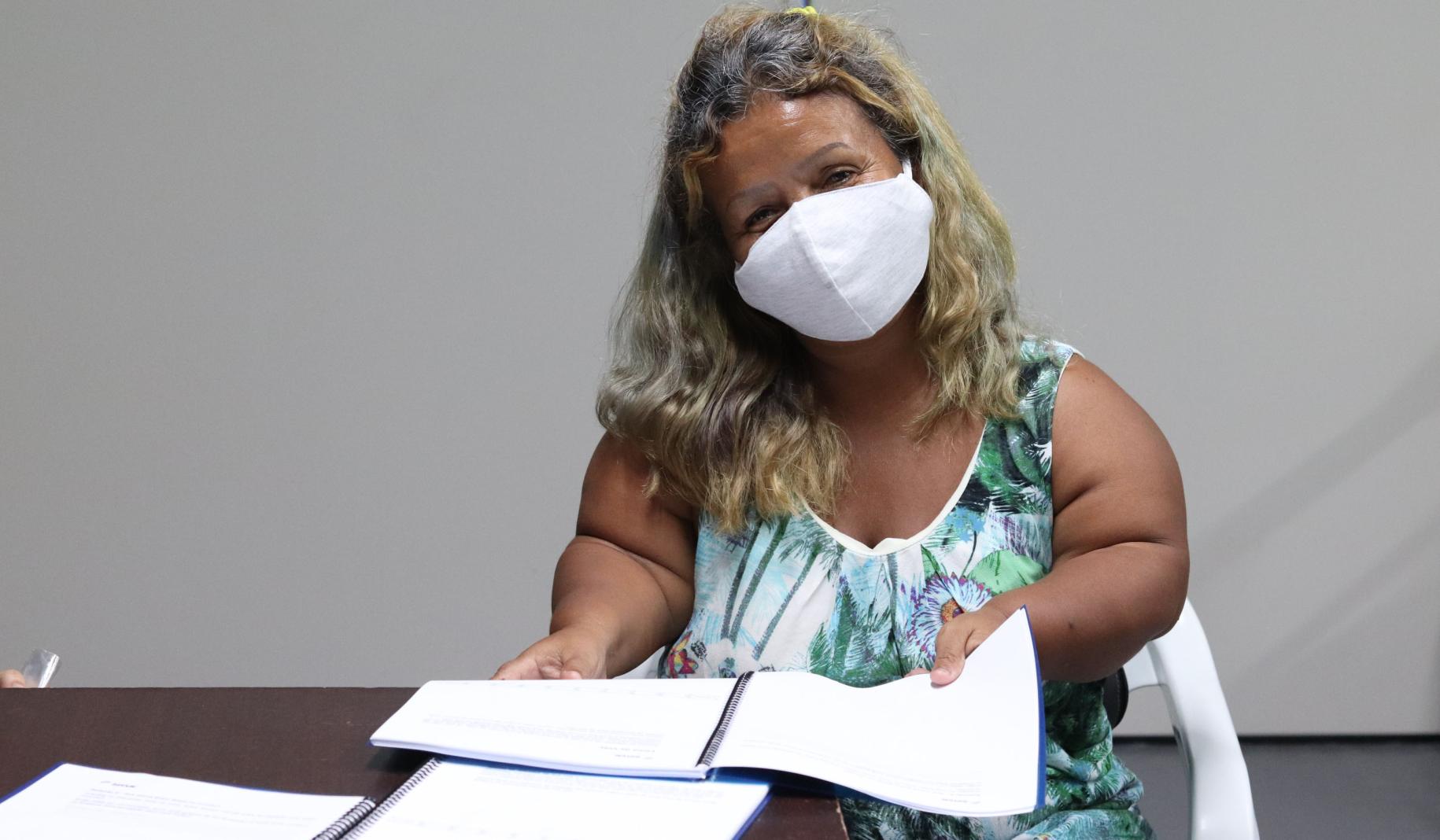 Carmen Bermúdez, de 50 años, sonríe detrás de su mascarilla mientras se sienta con los documentos de capacitación.