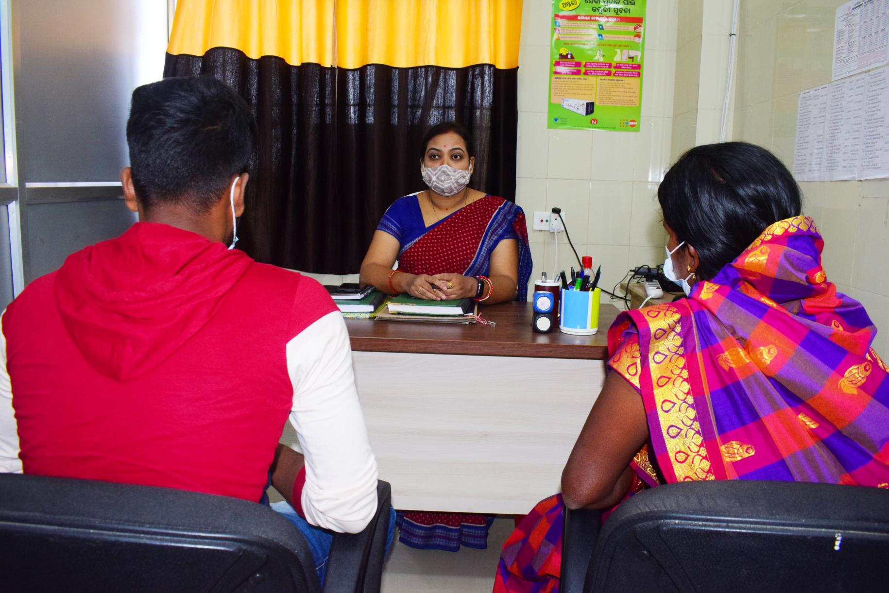 Una de los trabajadores de la salud, capacitados para asesorar, habla con los clientes en su oficina.