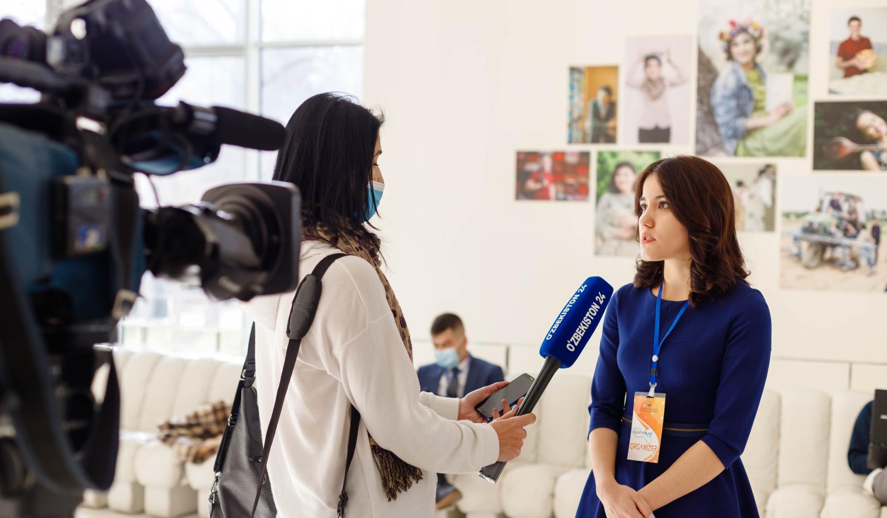 A young woman is being interviewed by a television reporter. 