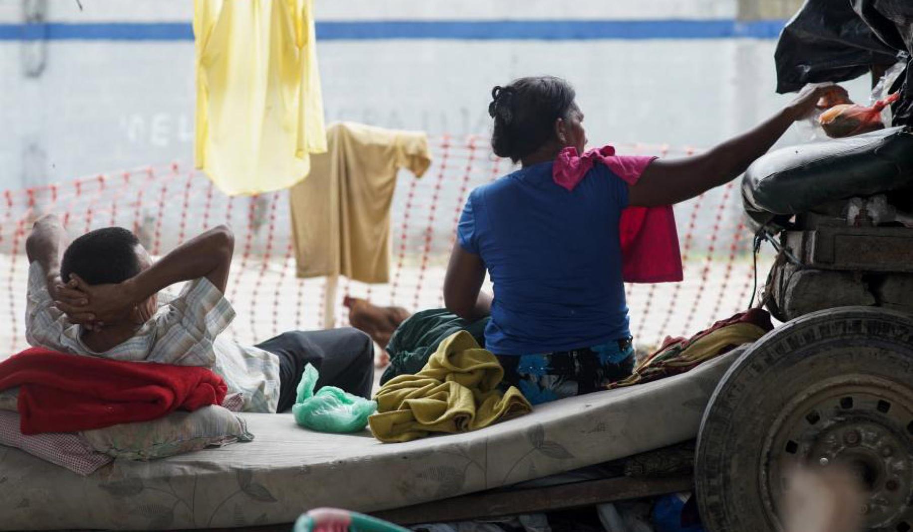 Un homme est à moitié allongé sur un matelas à gauche de l’image. Une femme est assise à sa droite. On leur a porté secours lors de la tempête tropicale qui a frappé le Honduras.