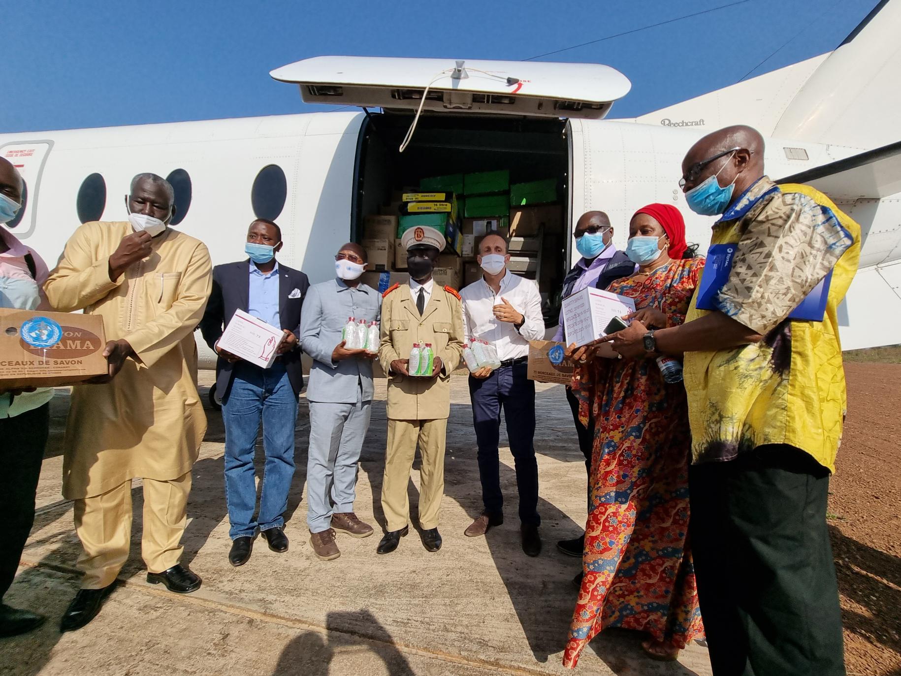Funcionarios y autoridades de la ONU en Guinea se encuentran frente a un avión de carga con suministros.