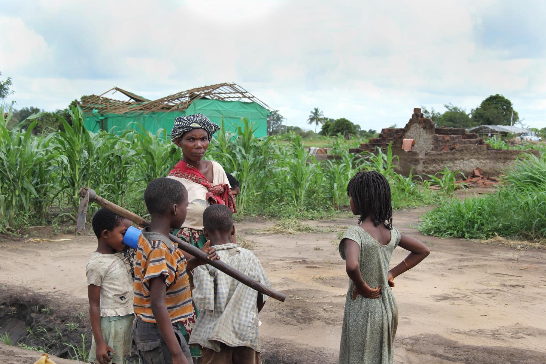 أم مع أطفالها تقف في الخارج بجانب حقولهم بعد إعصار ألويس.