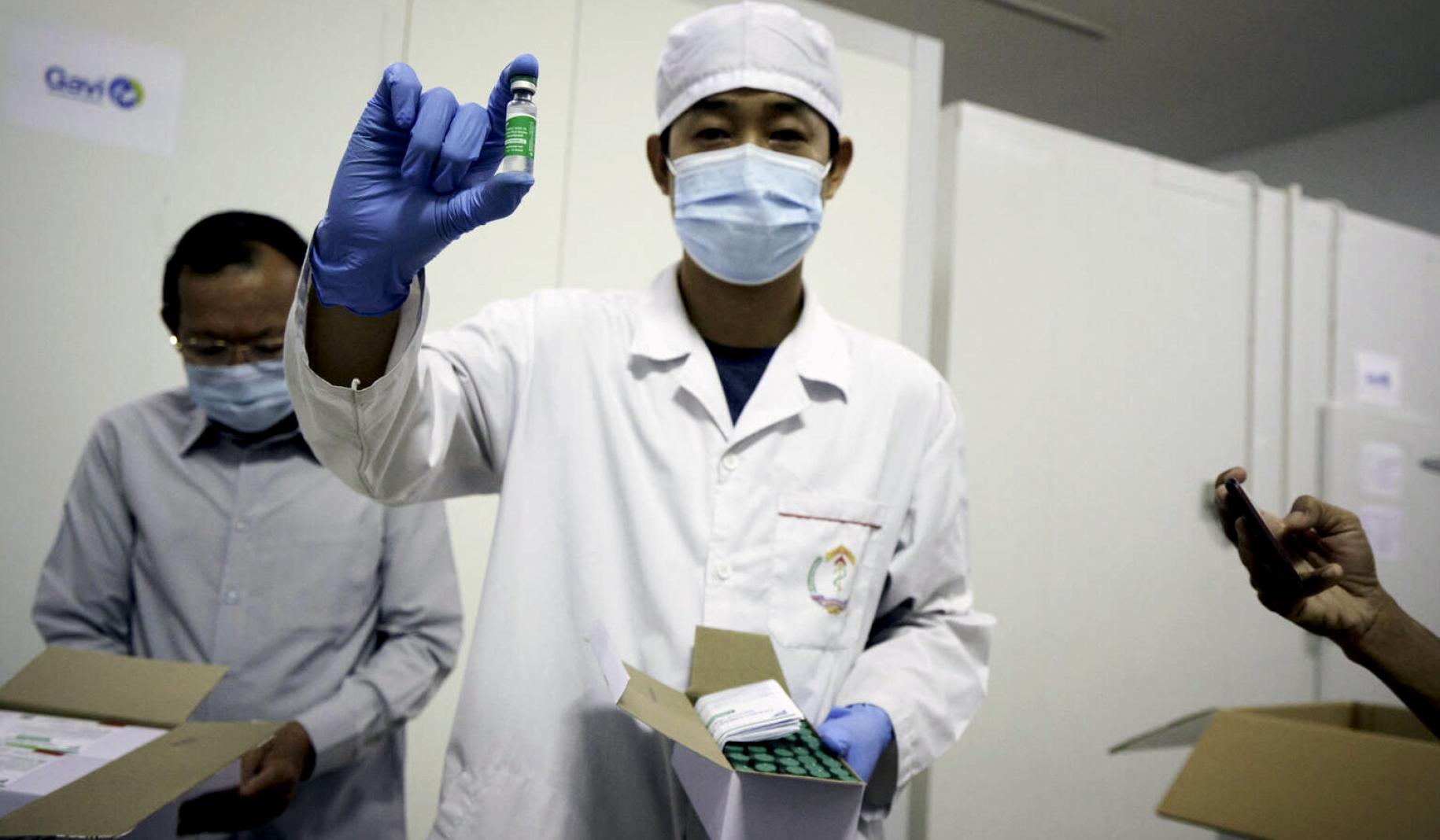 A healthcare professional holds up a vial of the COVAX-backed vaccine delivered to Cambodia.