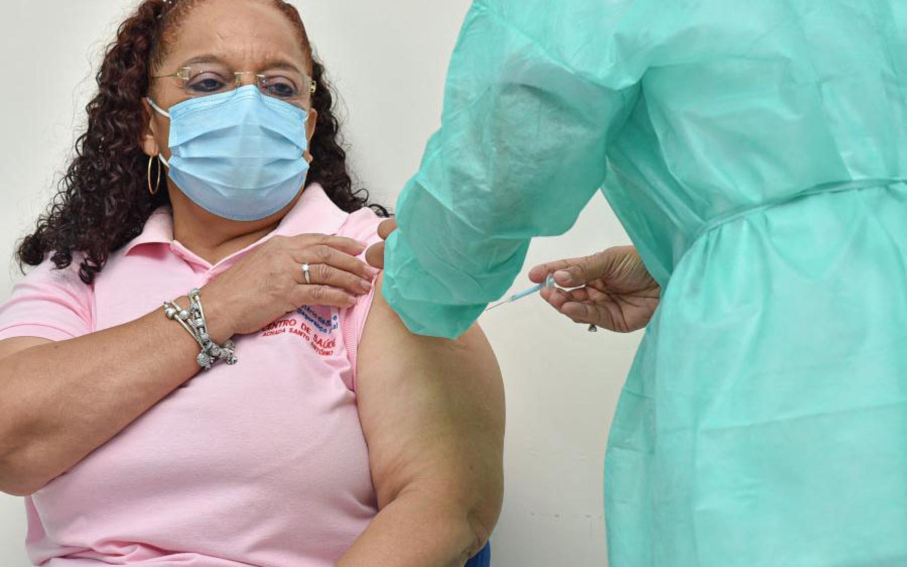 La enfermera Helga Fontes se arremanga mientras un trabajador de la salud le inyecta la vacuna contra COVID-19.