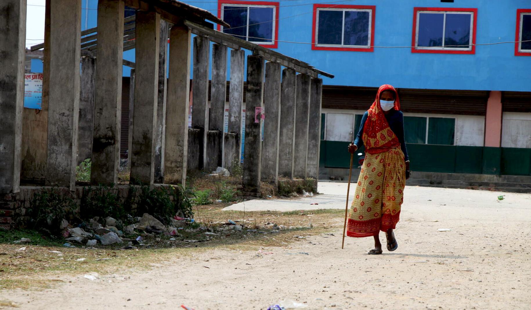 69-year-old Ashiya Devi Chaudhary carries a cane as she walks to get vaccinated against COVID-19. 