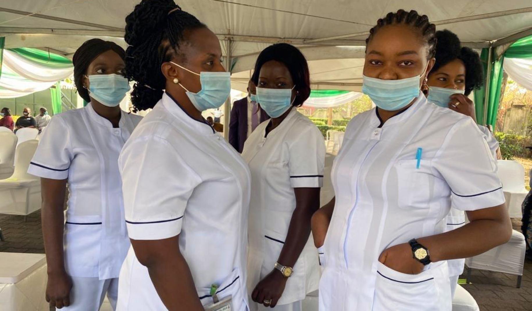 Healthcare workers wearing face masks stand together underneath a tent.