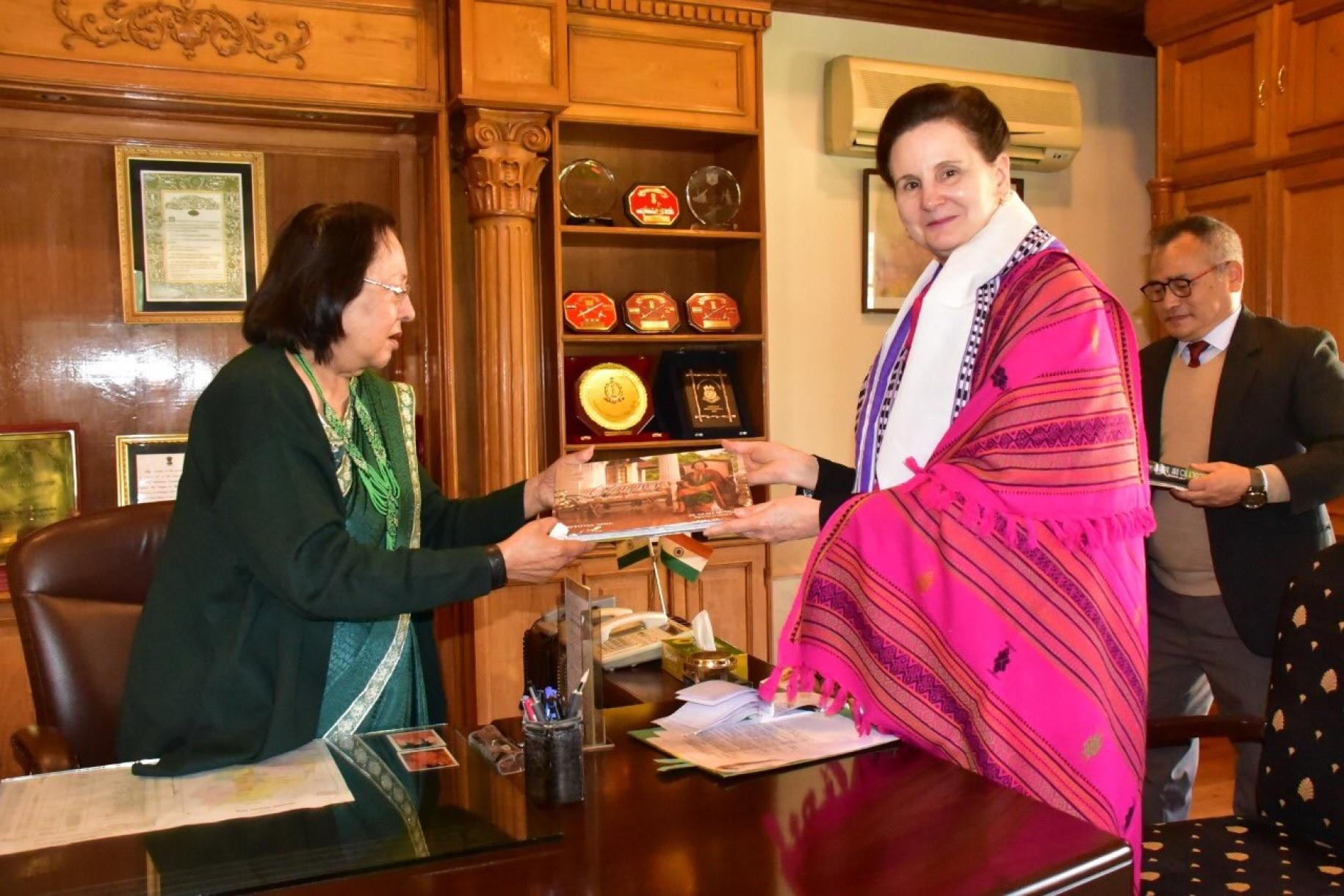 حاكمة مانيبور، على اليسار مرتدية ثوبًا أخضر، تعطي وثيقة إلى المنسقة المقيمة في الهند التي ترتدي ملابس تقليدية وردية اللون