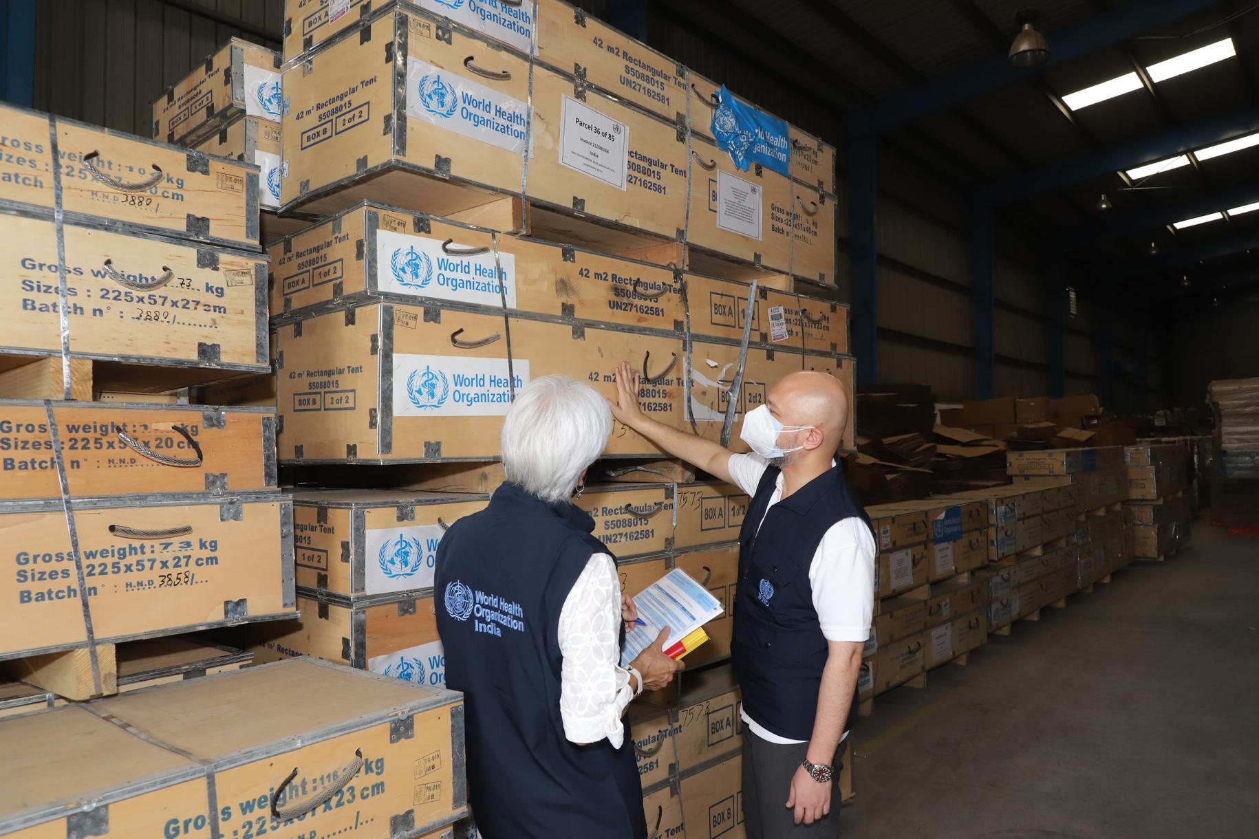 Dans un hangar de New Delhi, en Inde, deux membres du personnel de l’OMS inspectent une importante cargaison de fournitures médicales livrées au pays avec l’appui de leur Organisation.