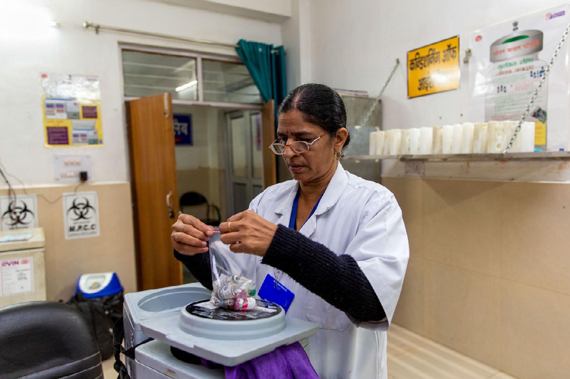 Dans un établissement de santé indien, Amrit Kaur, agente de santé formée par le PNUD pour aider au fonctionnement du Réseau électronique d'information sur les vaccins lancé par le Gouvernement indien dépose des flacons de vaccin dans un sac en plastique hermétique.