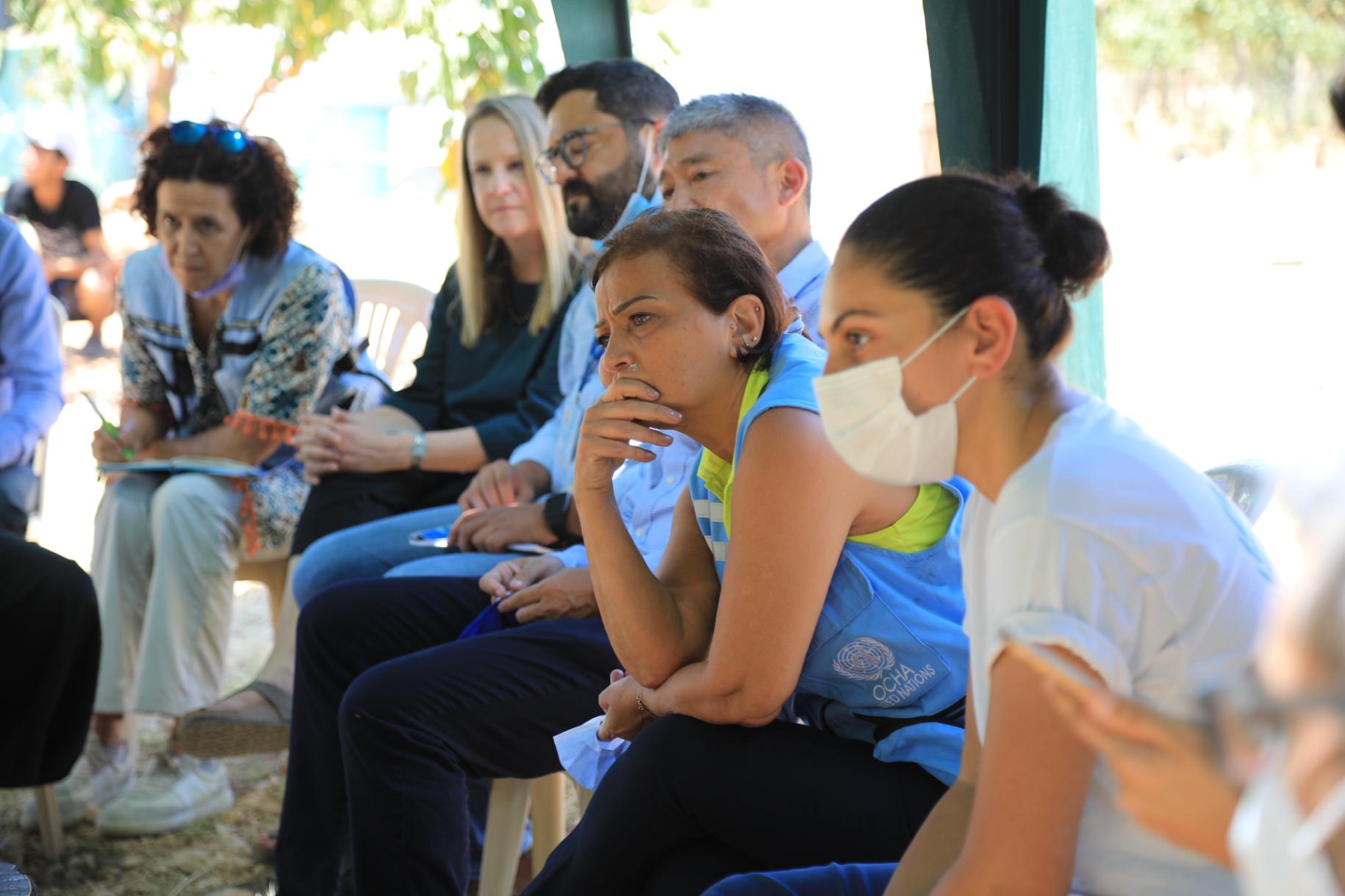 La Coordonnatrice résidente et Coordonnatrice humanitaire des Nations Unies au Liban, Najat Rochdi est entourée de plusieurs personnes et écoute attentivement les propos d’un interlocuteur assis devant elle, hors champ.