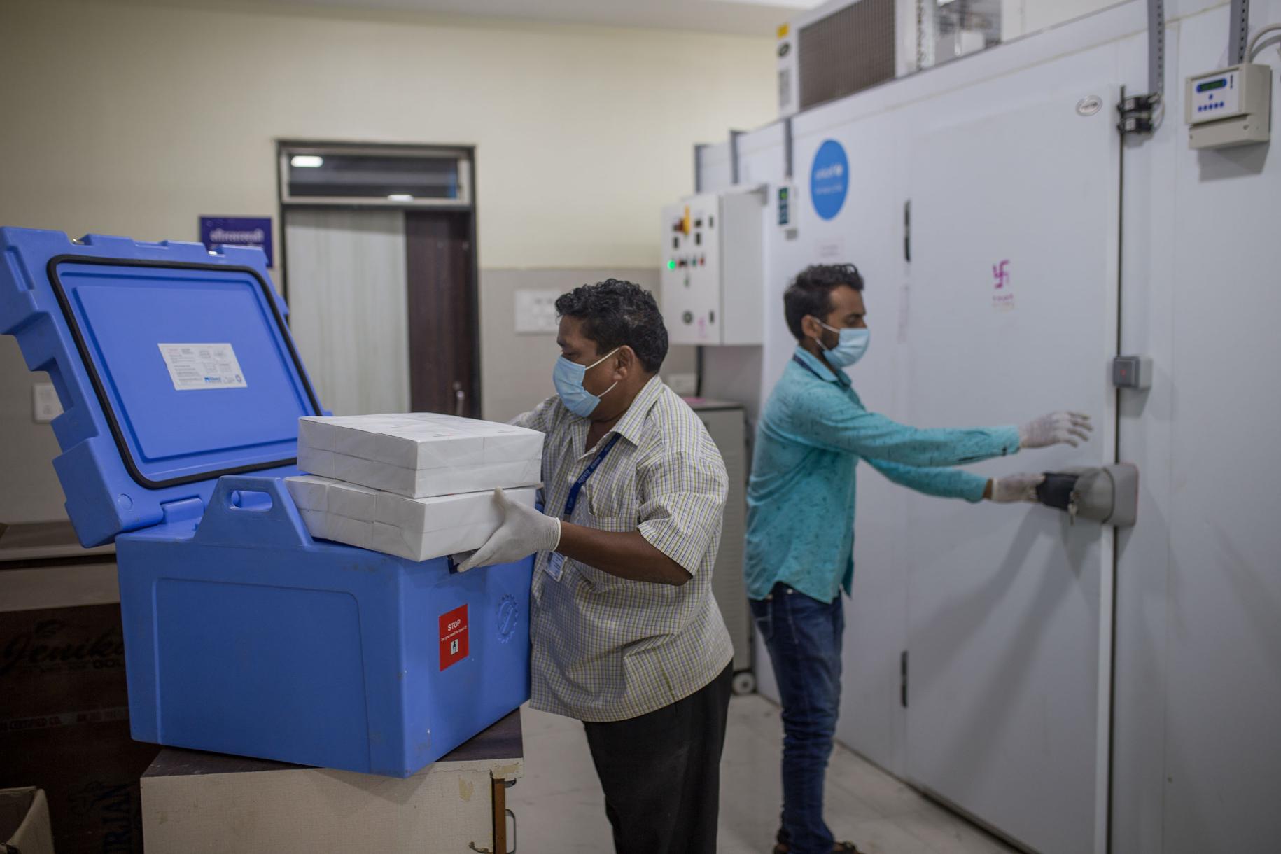 Au poste de la chaîne du froid du district de Maharashtra, le deuxième État le plus peuplé de l'Inde, deux employés d'État transfèrent des vaccins depuis des caisses de vaccins anti COVID-19 dans des chambres froides.