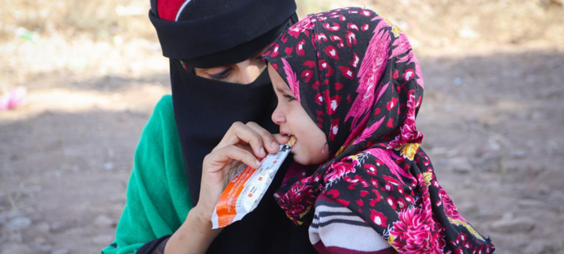 A woman feeds a young girl a nutritious snack. 