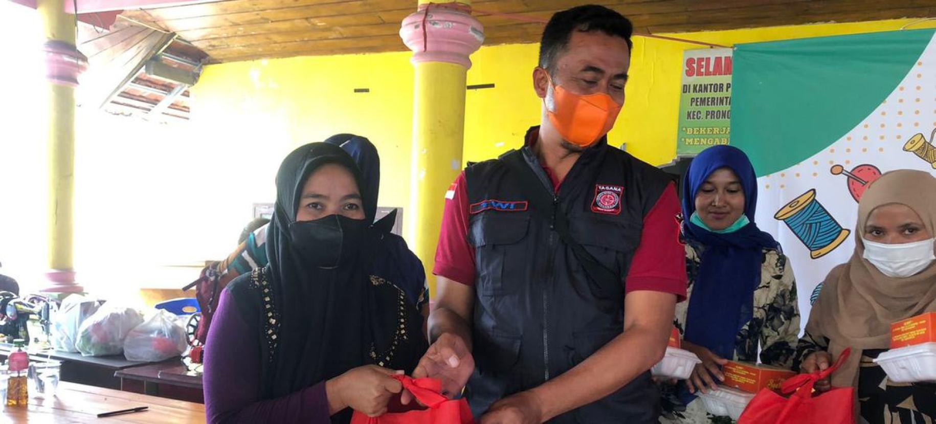 Un homme et une femme portant chacun un masque de protection respiratoire s’affairent avec d’autres personnes autour d’équipements de premiers secours.