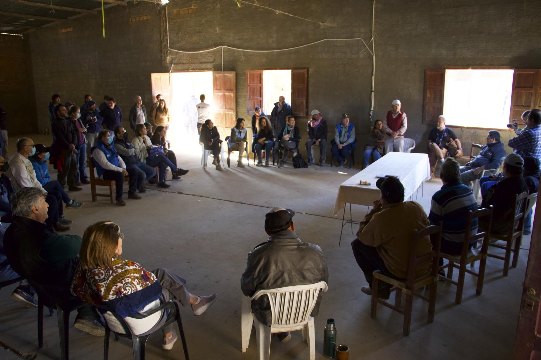 Un grupo de personas sentada en distribución circular en un espacio interior, ubicado en Santa Victoria Este, en Argentina.