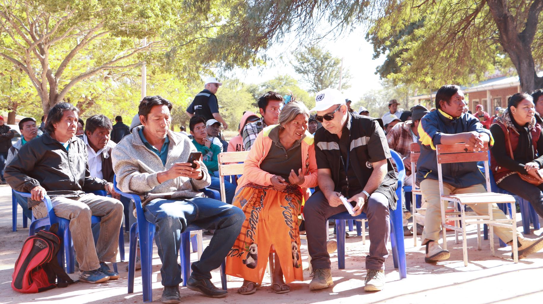 En un espacio exterior, con personas sentadas a manera de audiencia, una de las presentes, Catalina Martinez, de la comunidad nivacle en Paraguay, conversa con un colega de la OCHA.