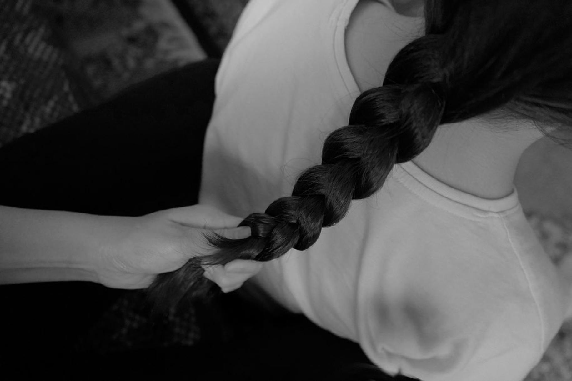 A girl's hair being braided by her mother.