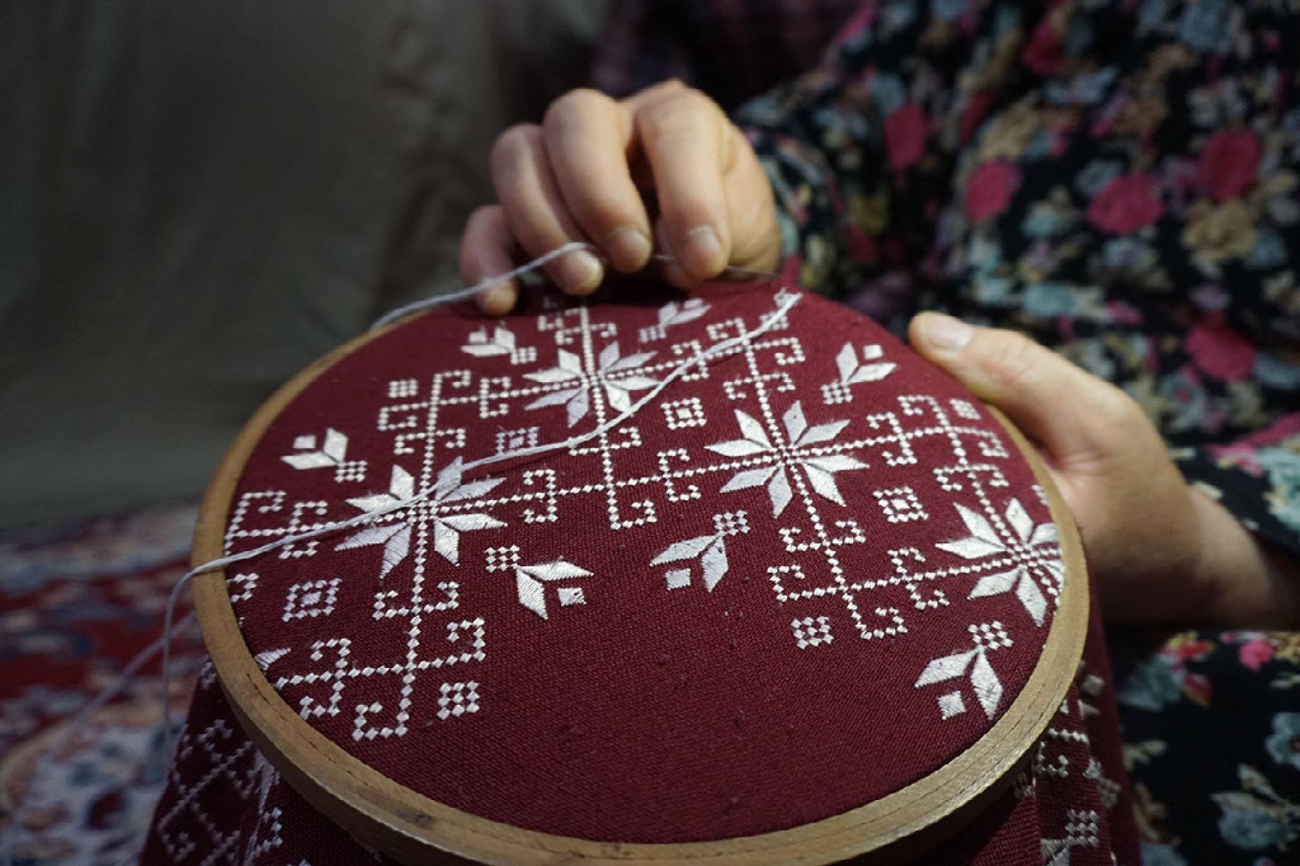  A clost shot of a pair of hands doing embroidery work. 