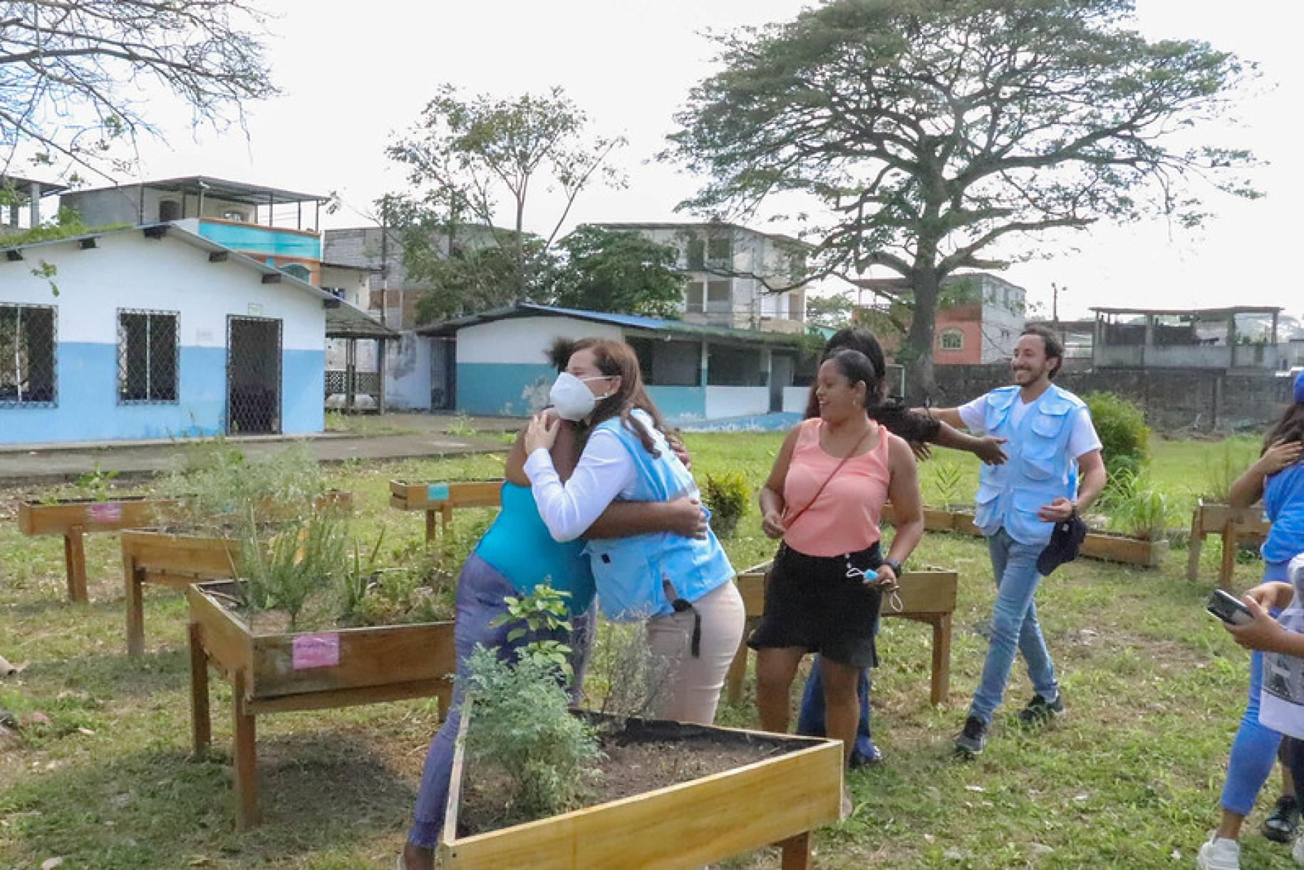 En una zona verde de la Unidad Educativa Walter Quiñonez, la Coordinadora Residente Lena Savelli y algunos colegas se reúnen con las mujeres que dirigen el huerto comunal.