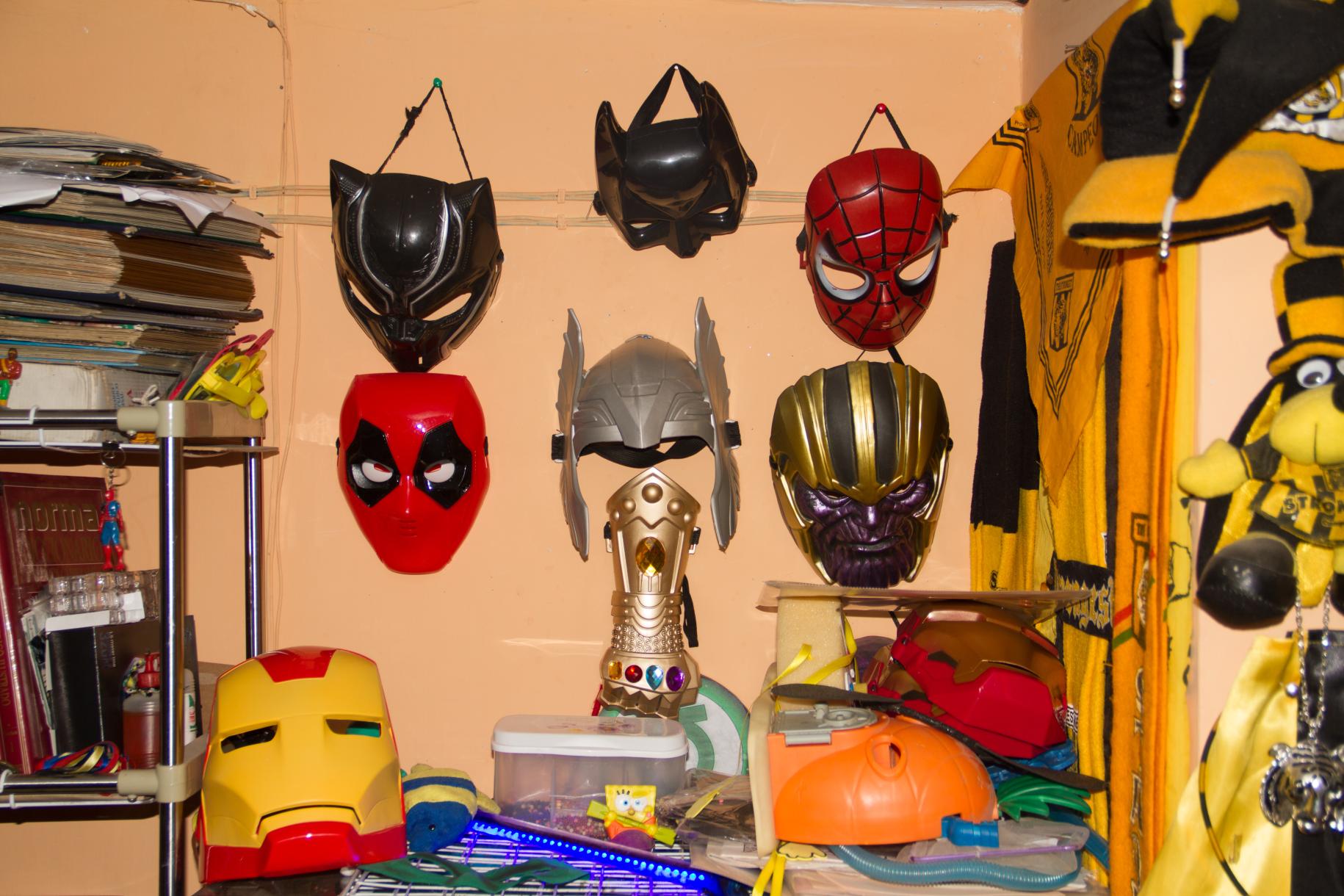 Una pared color melón con una colección de máscaras de superhéroes.