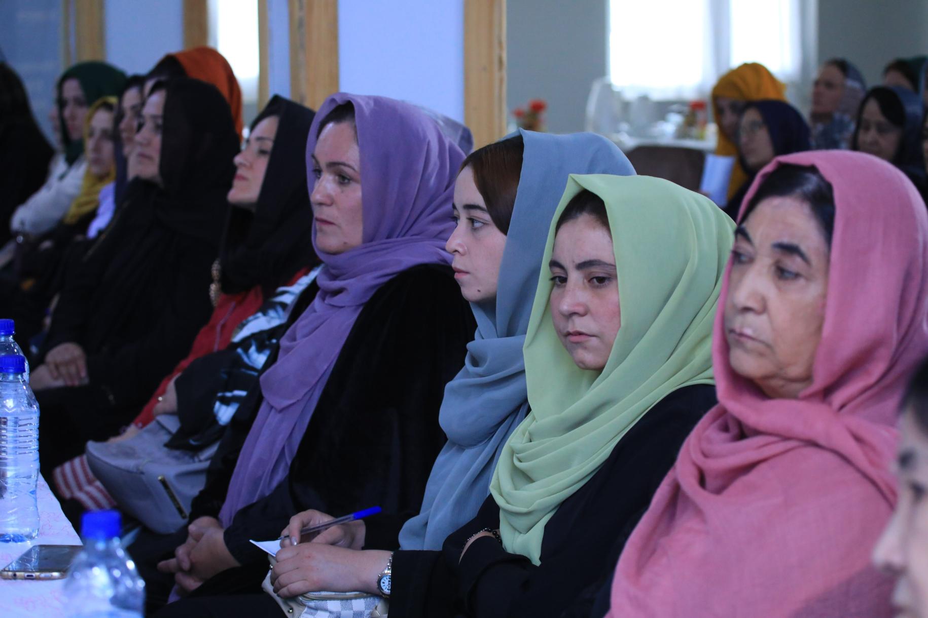 Mujeres con pañuelos de colores sentadas en fila.