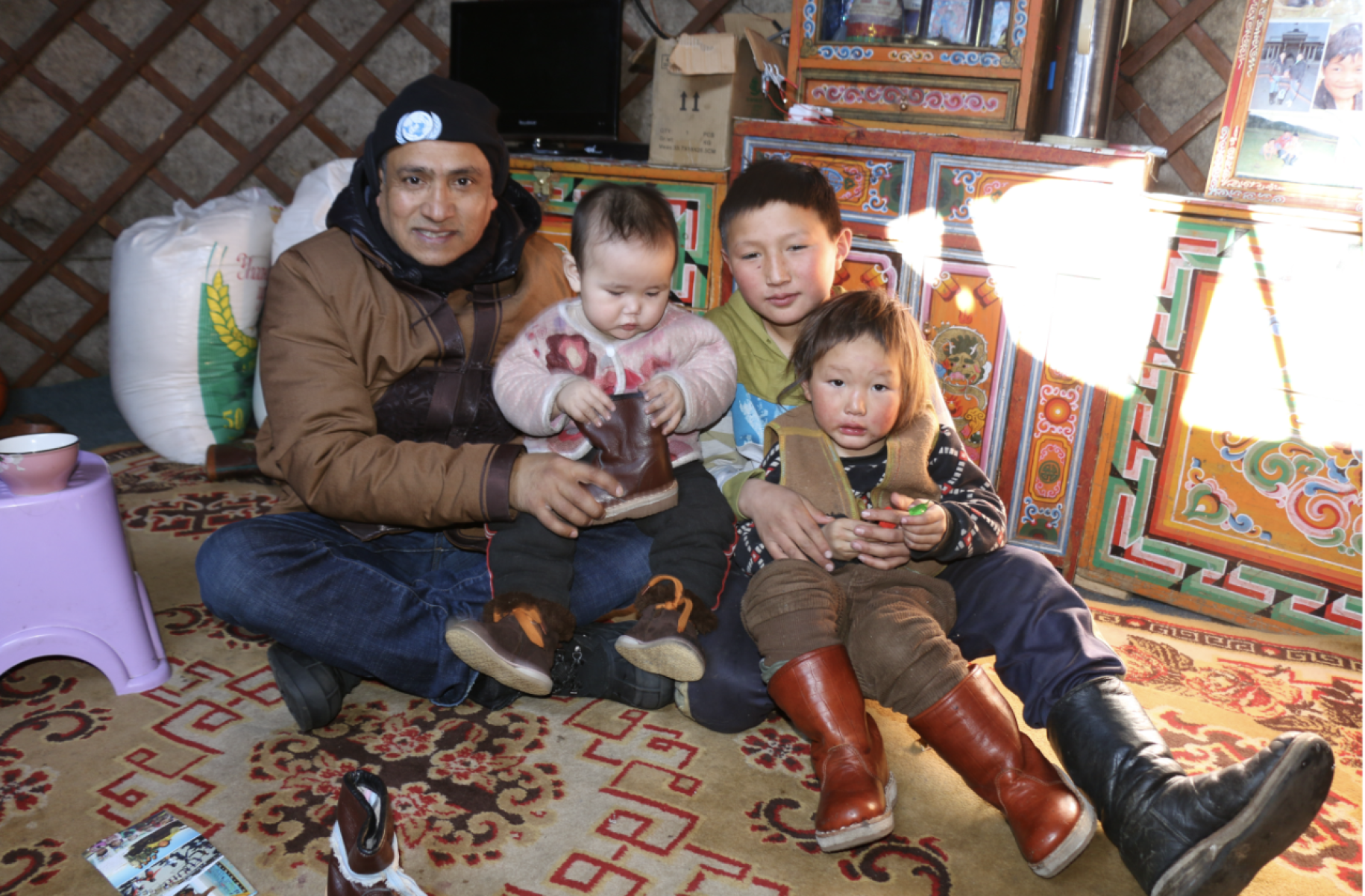 Man sits on carpet with three young children 