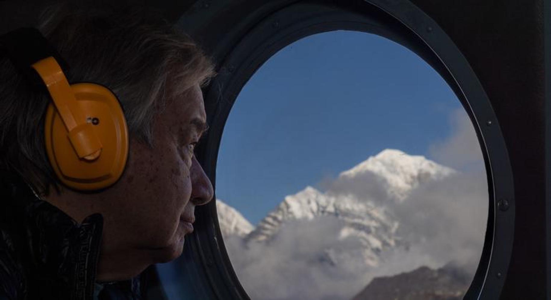 Антониу Гутьериш в профиль смотрит в иллюминатор на горы Непала