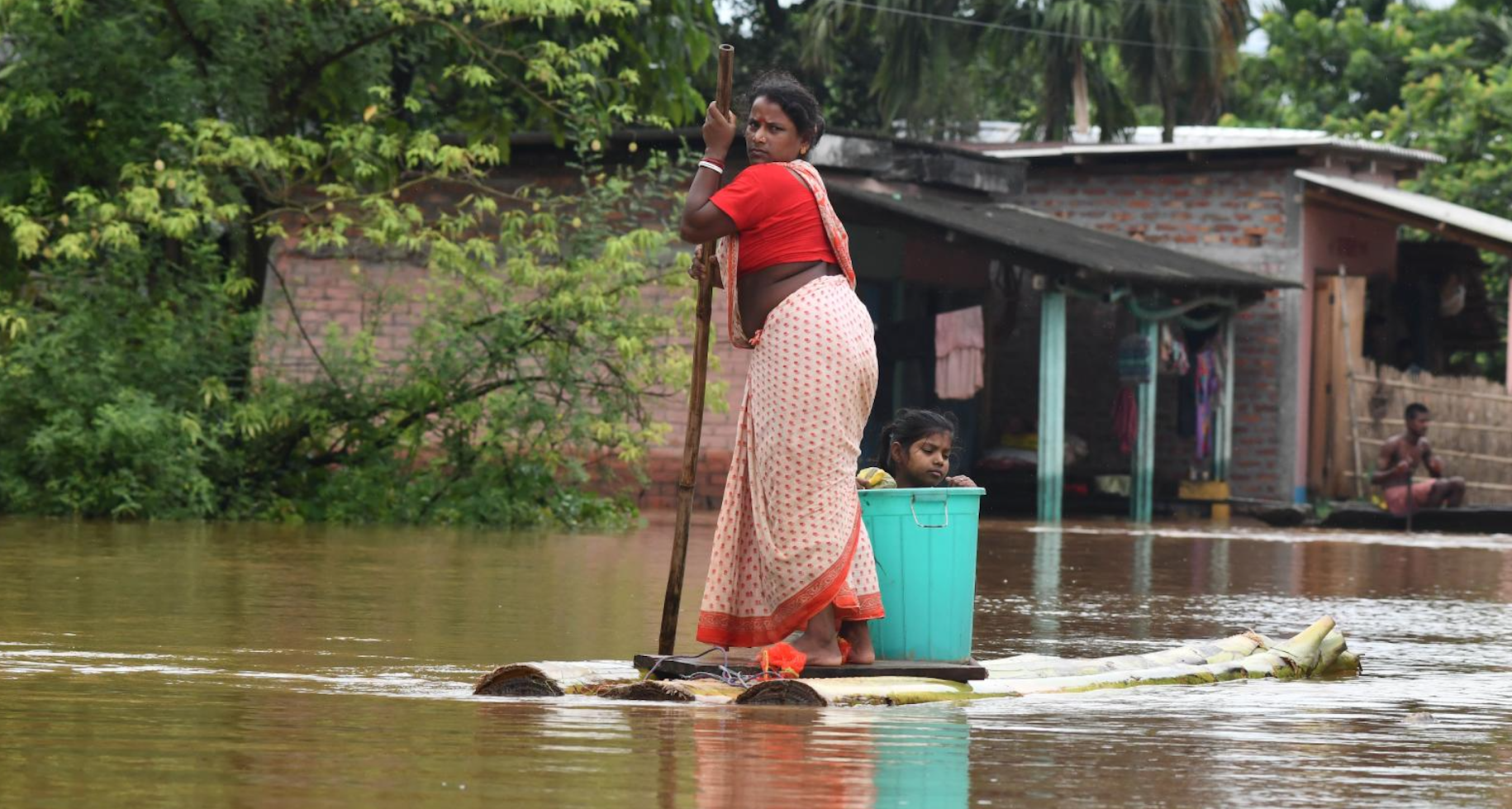 woman paddles a make-shift raft down a flooded street