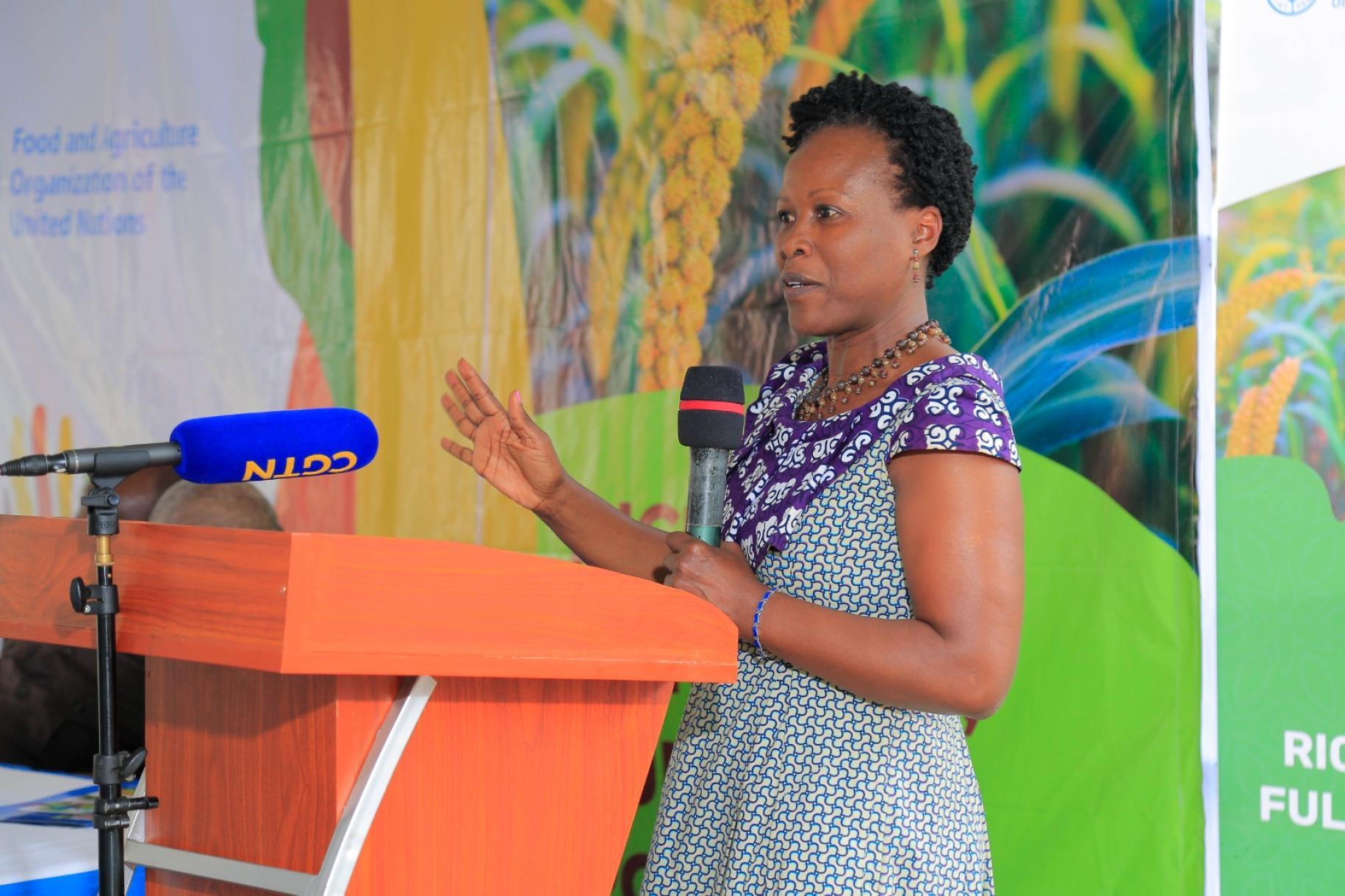 woman speaks at orange podium against a colourful wall 