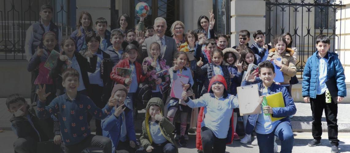School children gleefully and excitedly pose with the Resident Coordinator in front of the UN House in Azerbaijan.