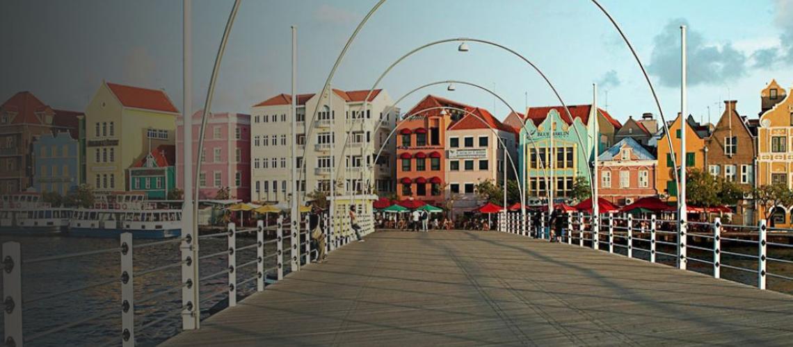 A scenic view of the Curaçao bridge leading up to bright and colourful buildings.