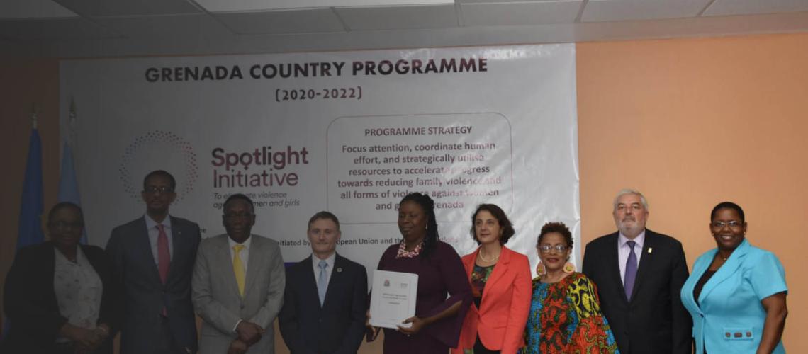 Representatives from the UN country team in Grenada stand together side-by-side in front of their Spotlight Initiative launch banner.