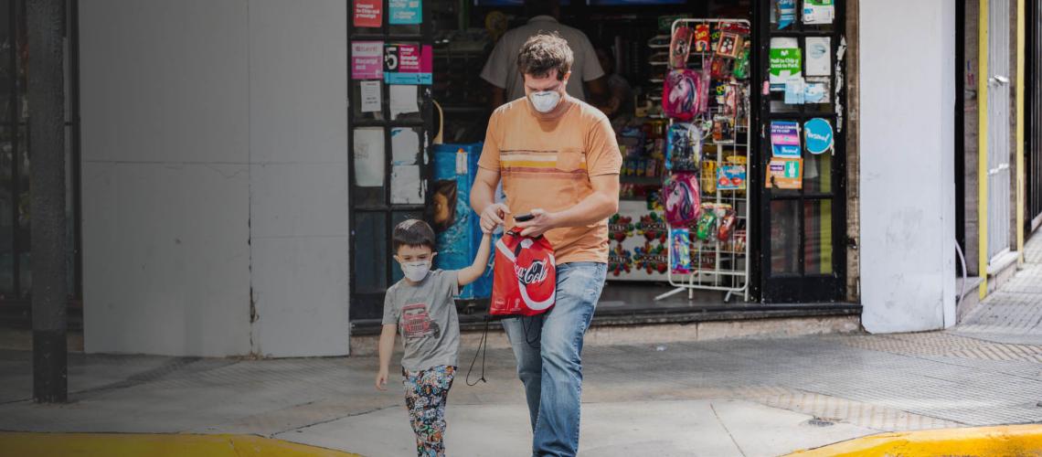 A father and son wearing face masks walk out of a store in Buenos Aires, Argentina.