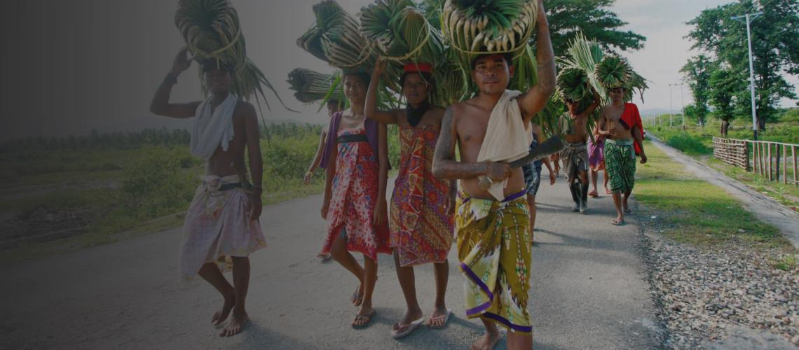 Un grupo de jóvenes timorenses llevando hojas de palmera para construir una casa sagrada tradicional.