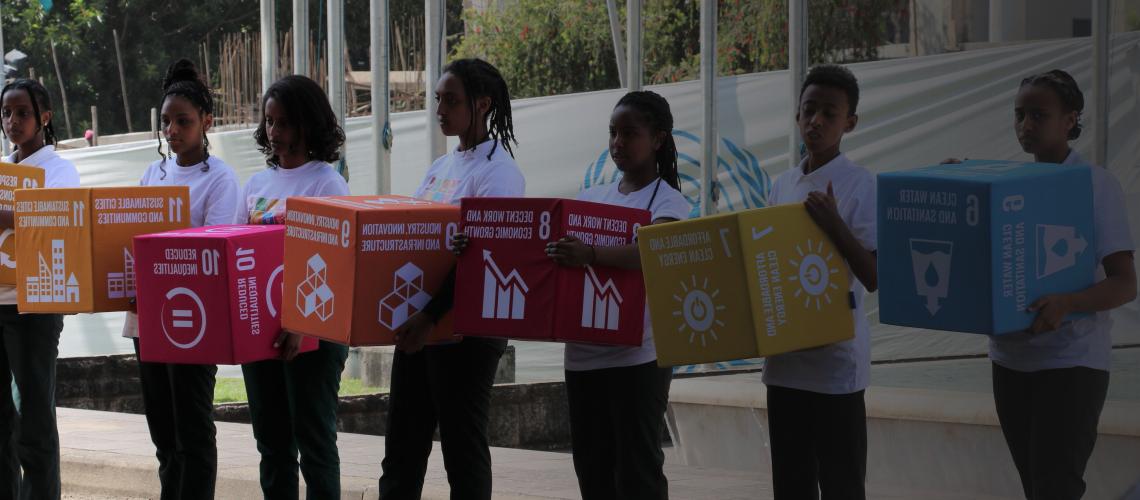تظهر الصورة شبابًا يحملون مكعبات عليها شعارات أهداف التنمية المستدامة.