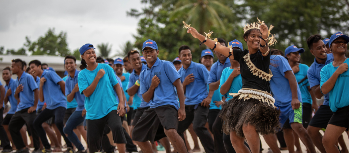 In Kiribati, young footballers dance with a girl in traditional dress at a UNFPA-supported tournament. 